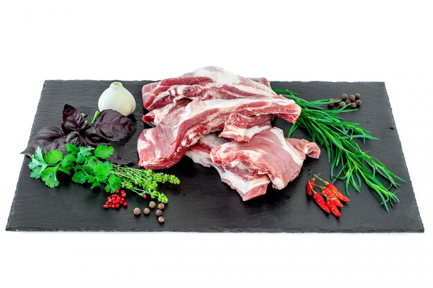 Raw pork ribs and condiments laid out on a black stone cutting board