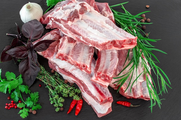 Raw pork ribs and condiments laid out on a black stone cutting board