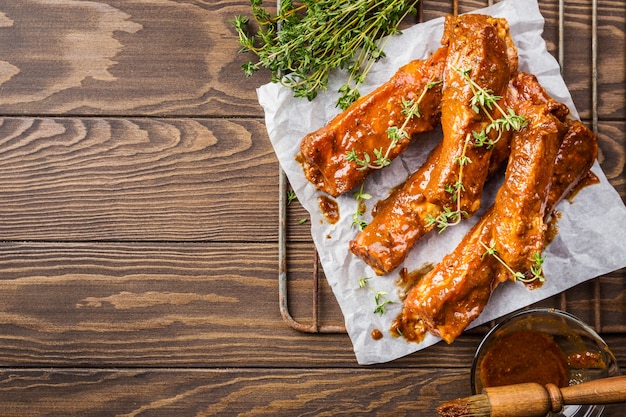 Raw pork ribs pickled in sauce with thyme on a dark wooden