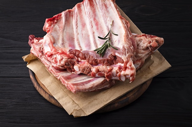 Raw pork ribs on a wooden board on a dark background