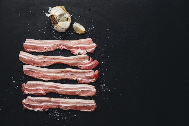 Photo raw pork slices with spices on dark. ready for cooking