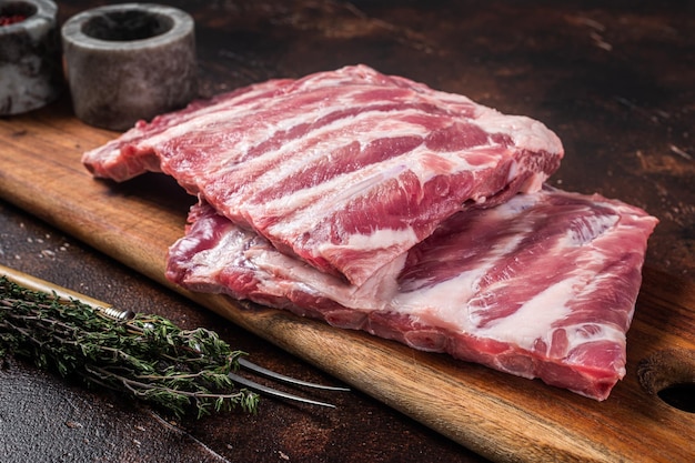 生の豚ロース肉のリブセントルイスのハーブと木の板暗い背景上面図