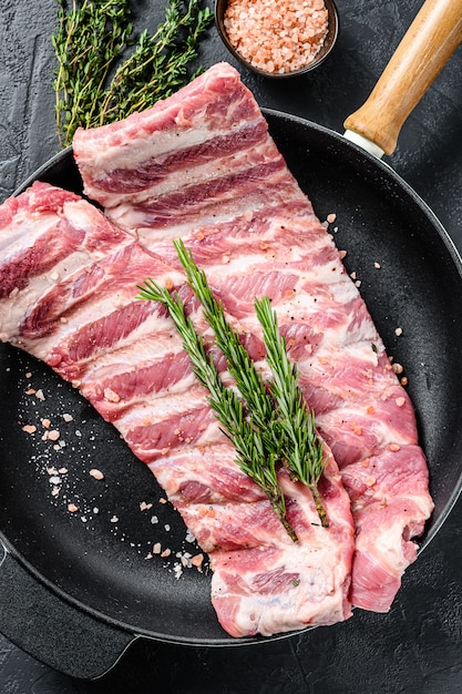 Raw pork spare ribs with spices and herbs in a pan.