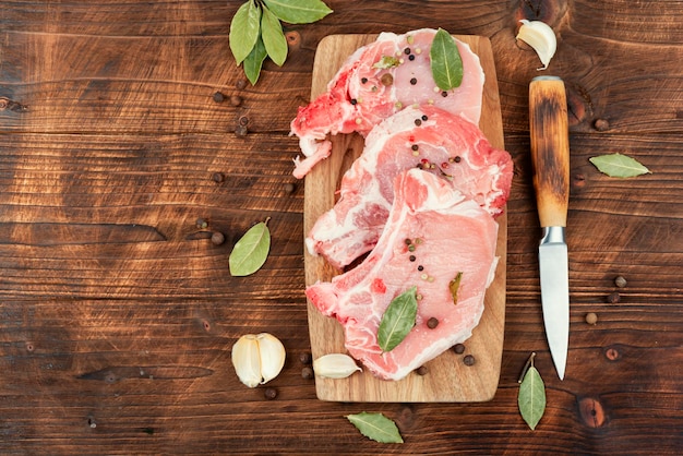 Foto bistecca di maiale cruda sull'osso su un tavolo di legno rustico lombo di maiale spazio di copia