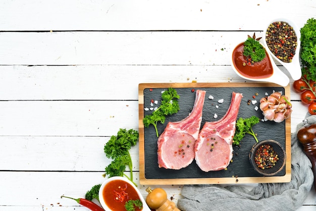 Raw pork steak on the bone On a stone board with spices and herbs Top view Free space for your text