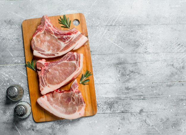 Premium Photo | Raw pork steak on the bone with rosemary.