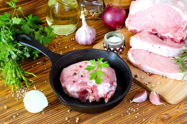 Raw pork steak in a frying pan on a kitchen table