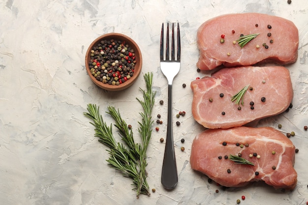 Raw pork steak, meat and ingredients for cooking, spices, herbs and vegetables on a light background. top view