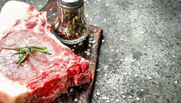 Bistecca di maiale cruda con erbe e spezie. su fondo rustico.