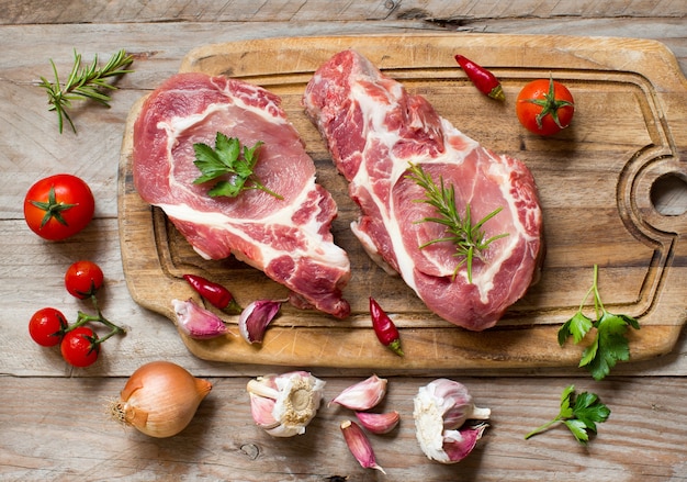 Raw pork steaks called  capicola with vegetables and herbs