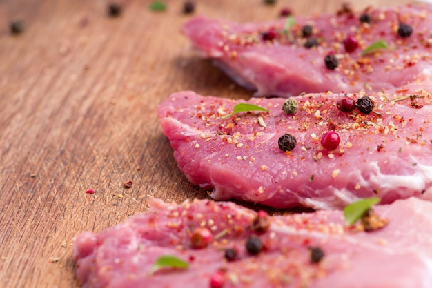 Raw pork steaks sprinkled with spices and herbs