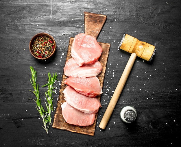 Raw pork steaks with spices and herbs. on the black chalkboard.