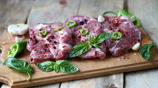 Raw pork steaks with spices on a wooden board