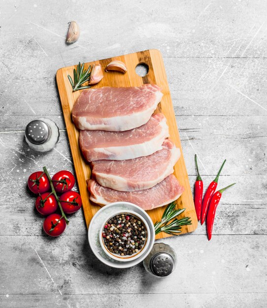 Raw pork steaks with tomatoes and spices