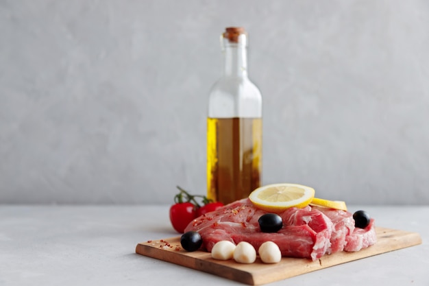 Photo raw pork steaks on a wooden board marinated in spices.