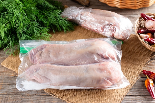 Raw pork tongue in a plastic bag on a wooden table. Concept of healthy eating