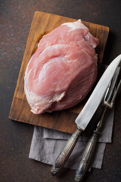 Raw pork on a wooden cutting board on a slate, stone or concrete.   