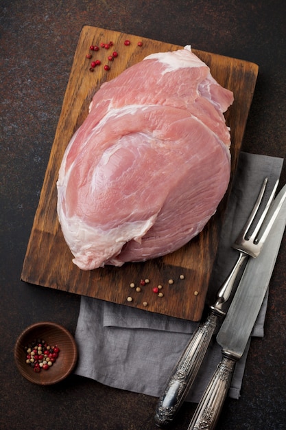 Raw pork on a wooden cutting board on a slate, stone or concrete.   