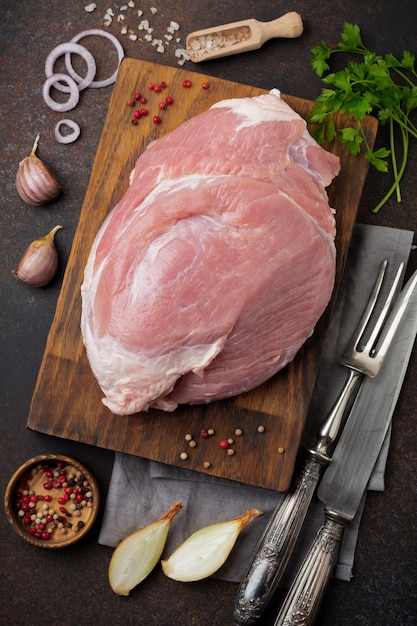 Raw pork on a wooden cutting board on a slate, stone or concrete.   