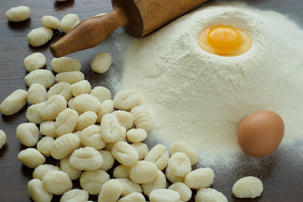 Raw potato gnocchi with eggs flour and rolling pin on a wooden table