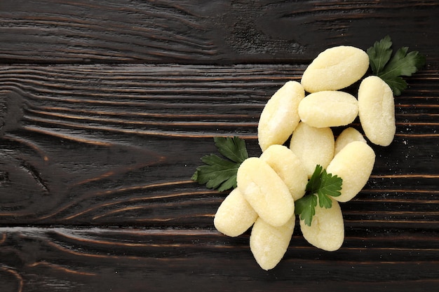 Raw potato gnocchi on wooden background space for text