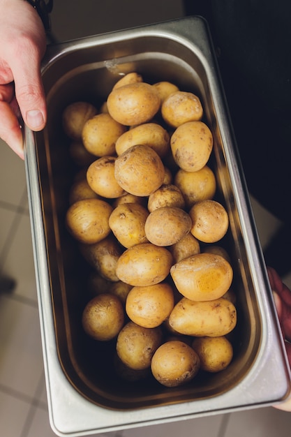 Raw potato in peel in the metal bowl.