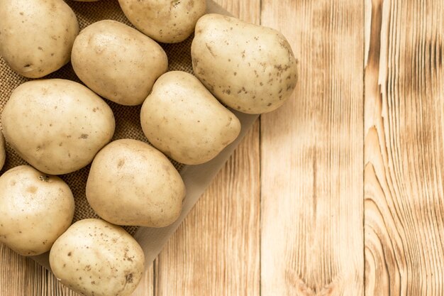 Raw potato tubers on a wooden background