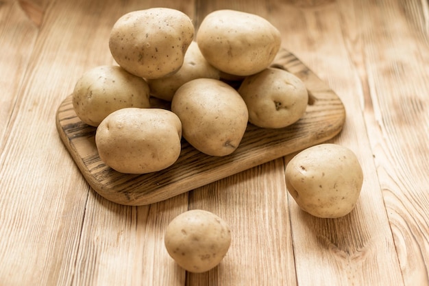 Raw potato tubers on a wooden background