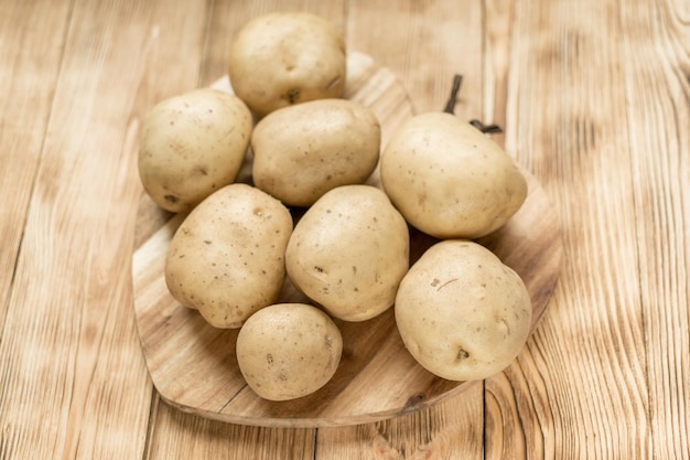 Raw potato tubers on a wooden background