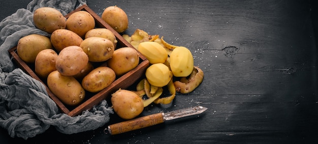 Foto patate crude su fondo di legno nero cottura spazio libero per il testo vista dall'alto