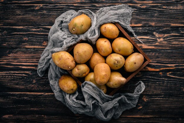 Raw potatoes On a brown wooden background Cooking Free space for text Top view