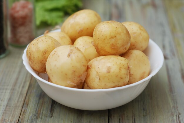 Raw potatoes on rustic wooden table.