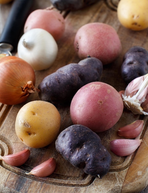 Raw potatoes and vegetables on a wooden board