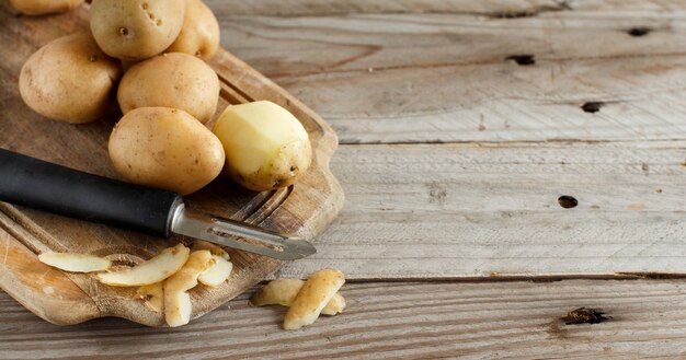 Raw potatoes with a vegetable peeler close up