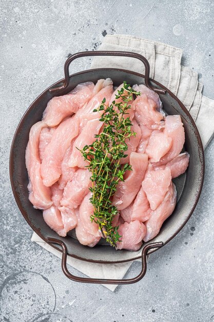 Raw poultry meat slices in a steel tray Gray background Top view