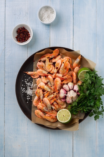 Raw prawns in cooking pan with ingredients for preparation fried shrimps top view