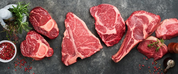 raw prime steaks variety of fresh black angus prime meat steaks tbone new york ribeye striploin tomahawk on black or gray stone background set of various classic steaks top view copy space