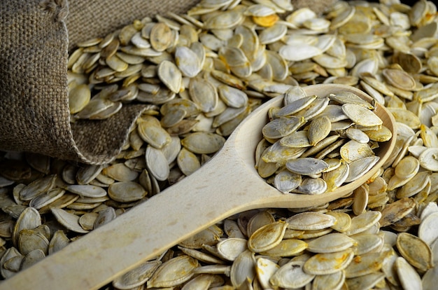 Raw pumpkin seeds close up in a wooden spoon