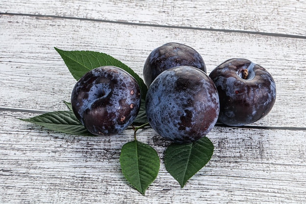 Raw purple plums heap with leaves