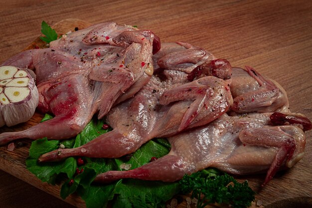 Photo raw quail meat on a cutting board with spices and herbs top view