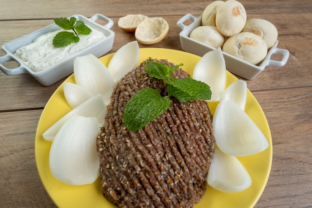 Raw quibe with sliced onion, dried curd, pita bread and mint leaves.