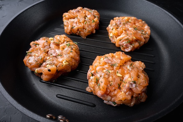 Raw quick asian salmon cutlets, on black textured background