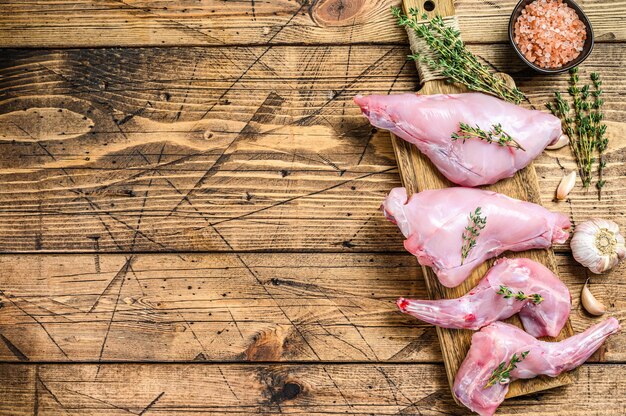 Raw rabbit legs on a cutting Board. Wooden background. Top view. Copy space.