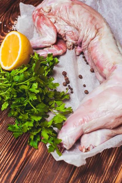 Raw rabbit meat with with lemon, salt and parsley on a wooden background