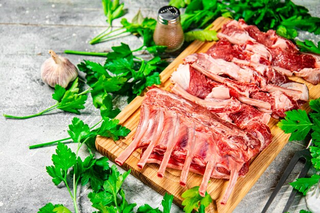 Raw rack of lamb on a wooden cutting board with parsley