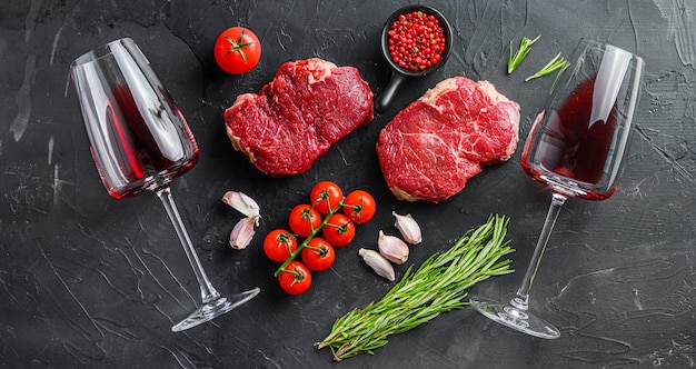 Raw ramp beef cuts with herbs and red wine glasses 