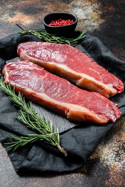 Raw ramp steak, fresh meat, marbled beef. Dark wall. Flat lay