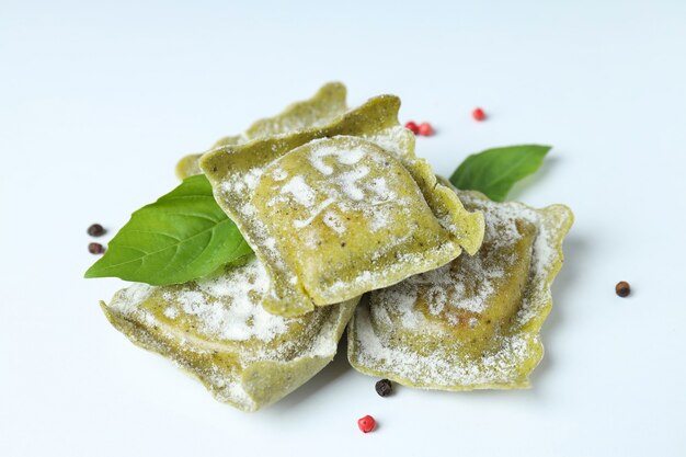 Raw ravioli with spices on white background