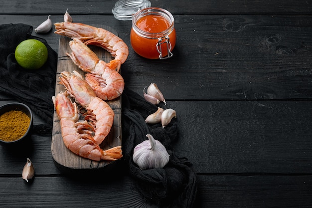 Raw red Argentinian prawns set, on wooden cutting board, on black wooden table