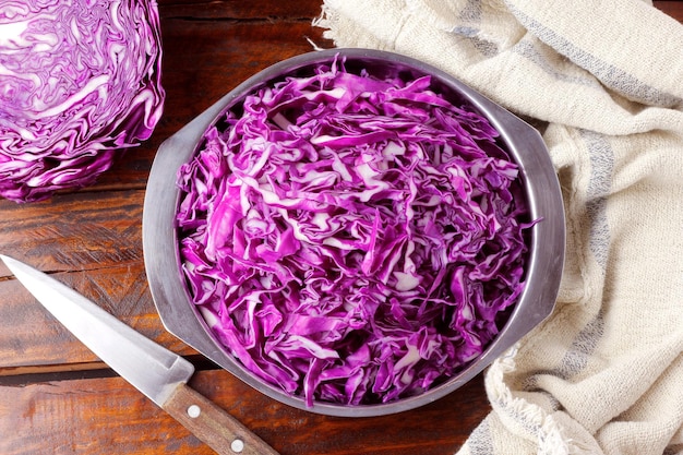 Raw red cabbage sliced in stainless bowl over rustic wooden table Top View